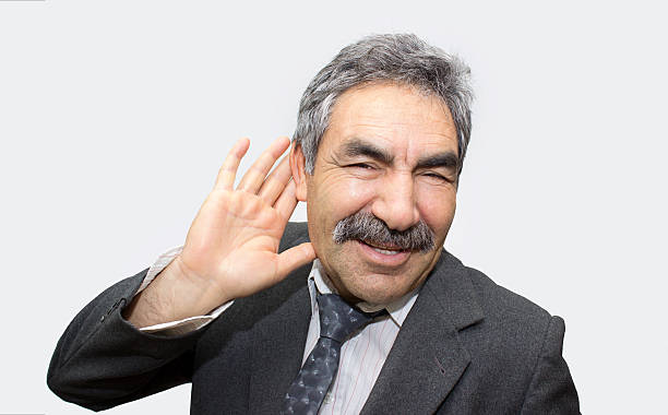 Portrait of mature man cupping his ear with his hands Portrait of mature man cupping his ear with his hands over colored background. Horizontal composition. Studio sho. Smiling businessman putting his hand around his ear and listening. old man cupping his ear to hear something stock pictures, royalty-free photos & images