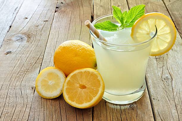 Cold lemonade with lemon slices and mint on rustic wood