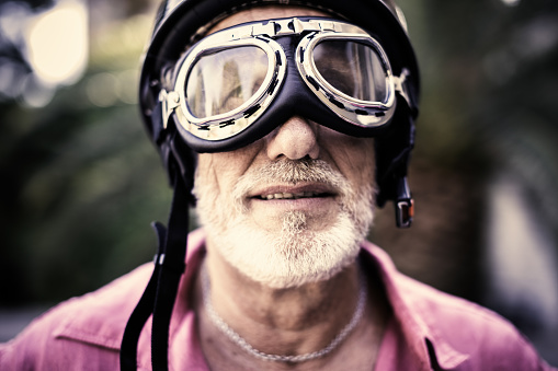 portrait of a senior racing driver wearing vintage helmet and glasses