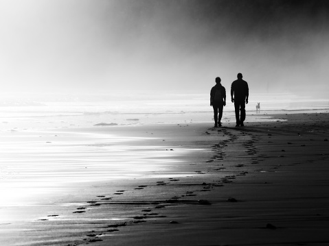 couple walking on foggy beach