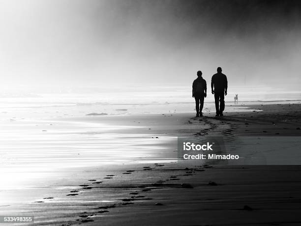 Couple Walking On Foggy Beach Stock Photo - Download Image Now - Footprint, Two People, Walking