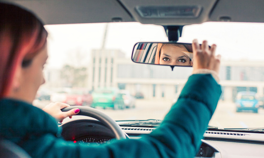 Teenage driver adjusting the rear view mirror
