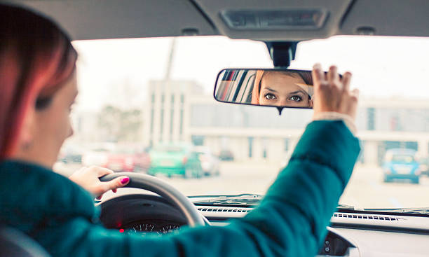 Adjusting the rear view mirror Teenage driver adjusting the rear view mirror rear view mirror stock pictures, royalty-free photos & images