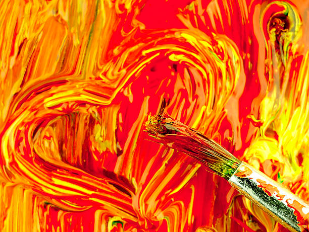 Paints and brush up on the pallet. Different colors mixed in a heart shape. Visible texture paint.