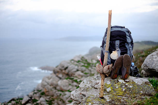 Backpack overlooking the Finisterre cliffs on the Camino de Santiago Hiking backpack, walking stick, and gear seated on a rock and overlooking the Atlantic Ocean in Finisterre, Spain. camino de santiago photos stock pictures, royalty-free photos & images