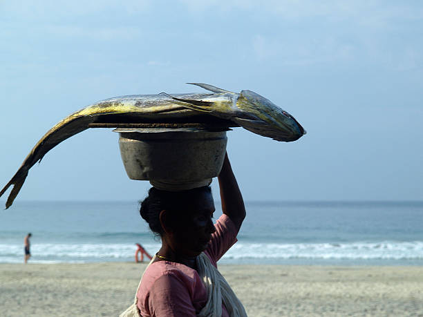 Kerala, India - February 22, 2005: A woman in Kerala, India, walking with a fish in a metal bowl on her head