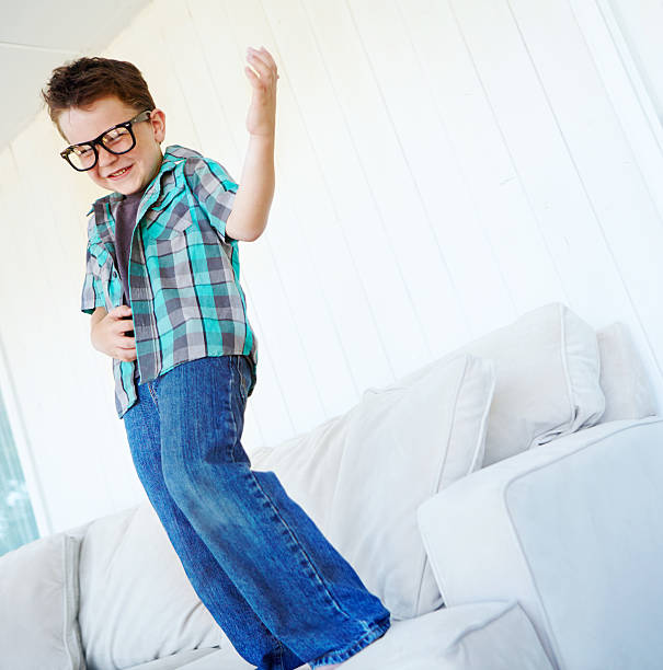 Playing my air guitar A cute little boy wearing glasses and playing air guitar on couch air guitar stock pictures, royalty-free photos & images