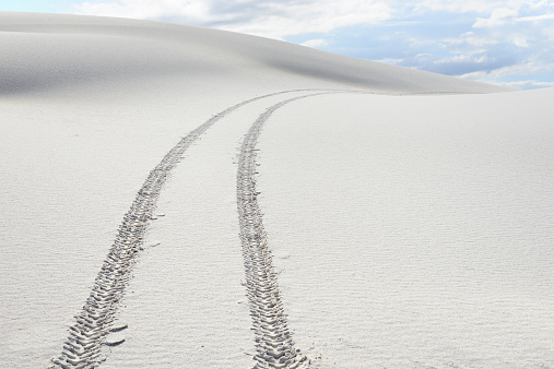 Single car tracks through remote sand dunes at White Sands National Monument, New Mexico.