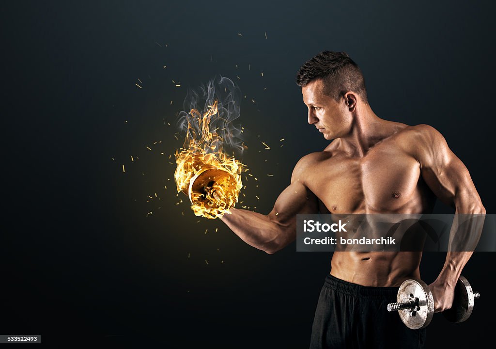 Muscular man with dumbbells on dark background Handsome power athletic man bodybuilder doing exercises with dumbbell. Fitness muscular body on dark background. 2015 Stock Photo