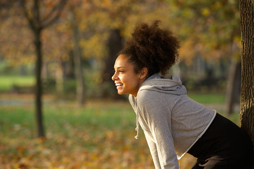 Portrait of a young woman smiling and resting after workout in the park