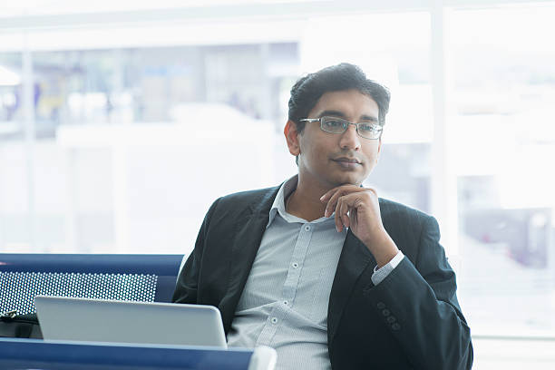 Indian business man having a thought at airport Asian Indian business man waiting his flight at airport. india airport stock pictures, royalty-free photos & images