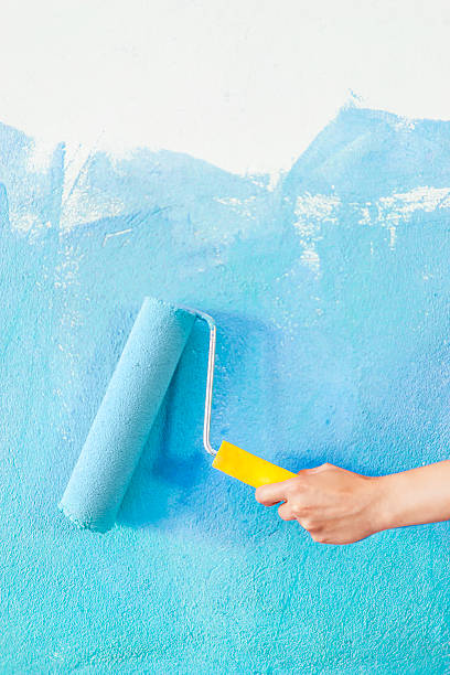 istock Female hand painting a wall in blue 533553198