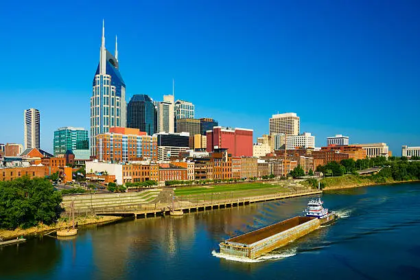 Photo of Nashville skyline, river, and barge ship