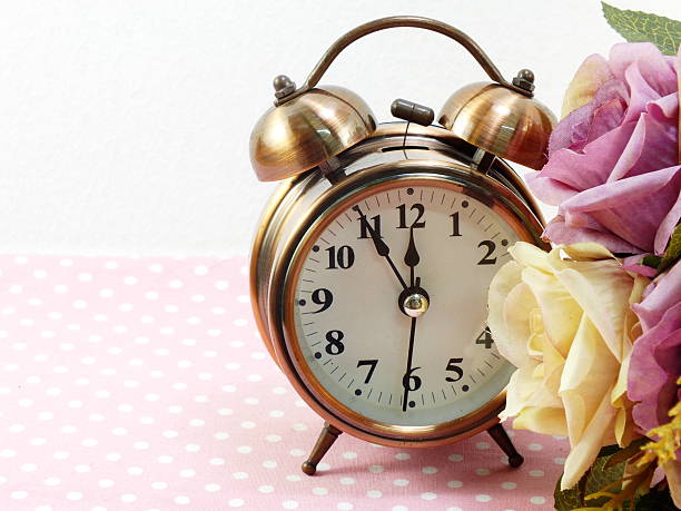istock spring time with alarm clock and artificial flowers bouquet background 533566128