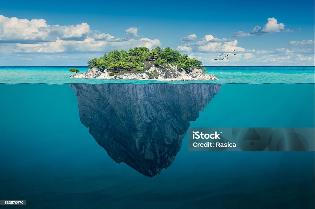 Idyllic solitude island with green trees in the ocean Beautiful underwater view of lone small island above and below the water surface in turquoise waters of tropical ocean. Island Stock Photo