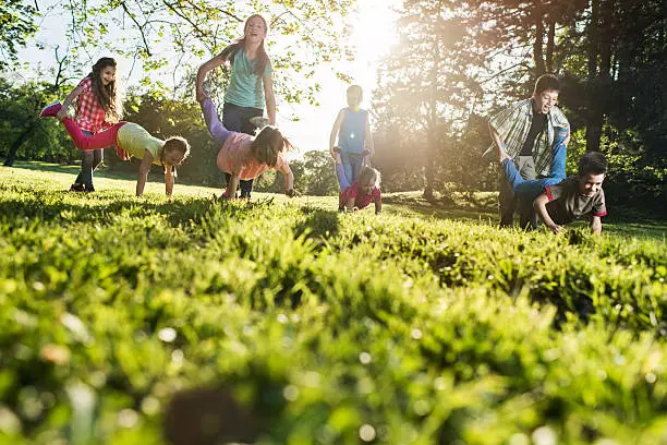 Photo of Below view of playful children having fun in wheelbarrow race.