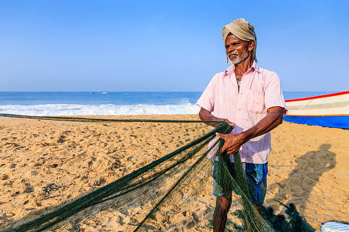 Indian fisherman at work. Fisherman are checking and repairing fishing net, Kerala, India.