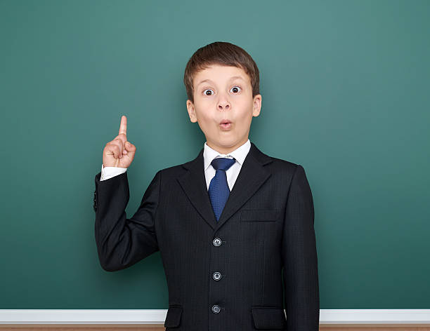 istock school boy show finger up gesture, point on green chalkboard 533576148