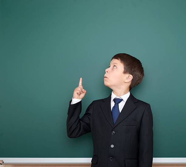 istock school boy show finger up gesture, point on green chalkboard 533576870