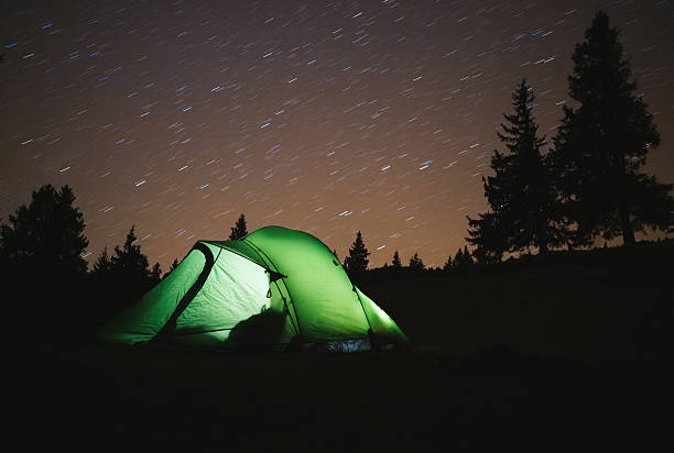 istock Green tent light in forest outdoor at night 533577604
