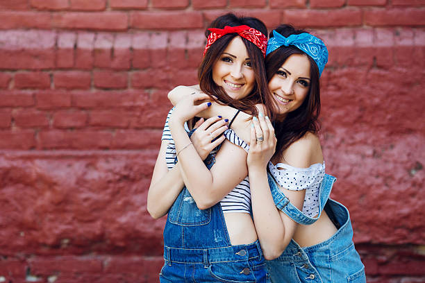 istock Brunette twins girls hugging on brick wall background. 533578216
