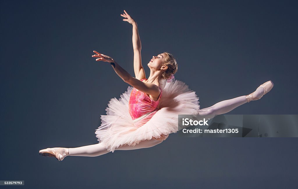 Beautiful female ballet dancer on a grey background. Ballerina is lBeautiful female ballet dancer on a grey background. Ballerina is wearing  pink tutu and pointe shoes Ballet Stock Photo