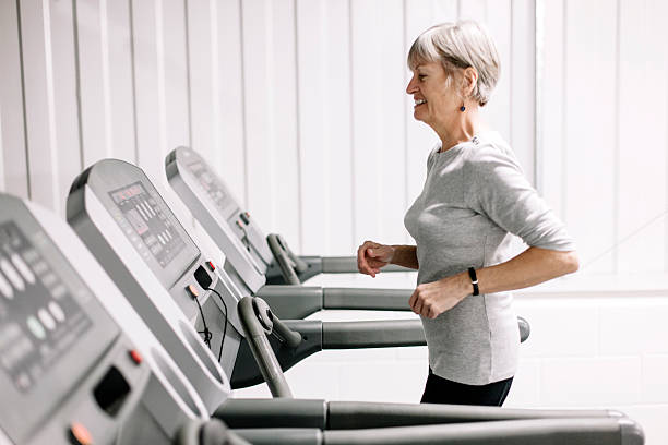 Using a running machine; beautiful, senior woman stock photo