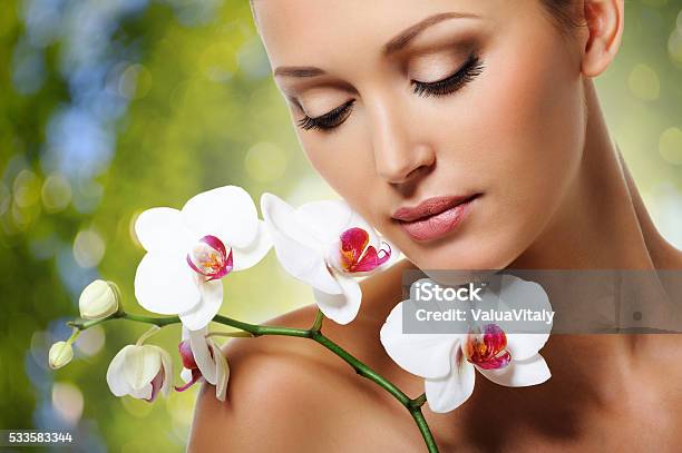 Face Of Beautiful Woman With A White Orchid Flower Stock Photo - Download Image Now