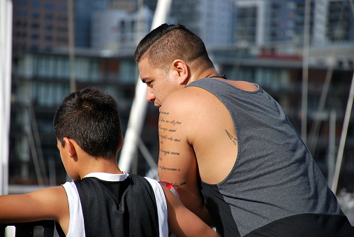A Polynesian Man and Boy having a chat whilst resting. This image is taken in the Wynyard Quarter in New Zealand's Auckland City.