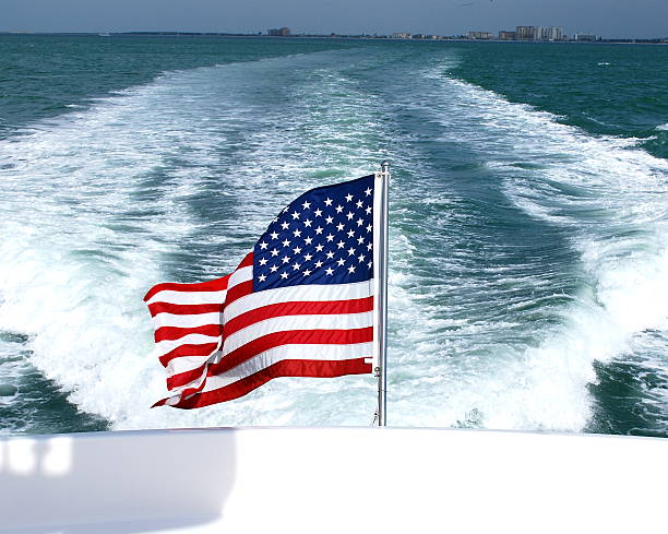 American Flag flying in wind behind a boat on water
