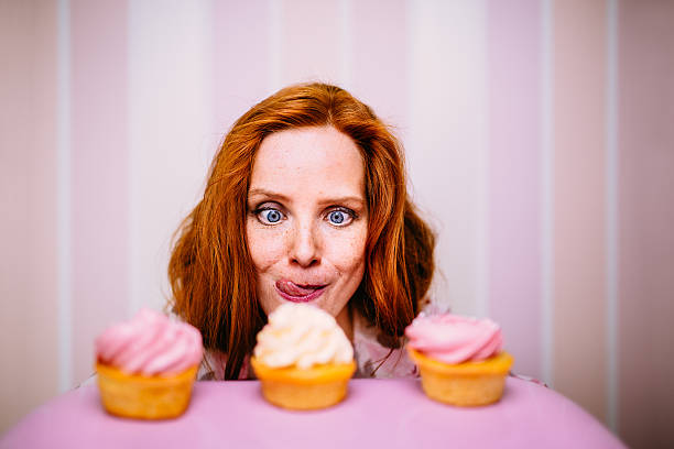 Young Woman Really Wants To Eat Cupcakes Young red head woman really wants to eat pink cupcakes sugar food stock pictures, royalty-free photos & images