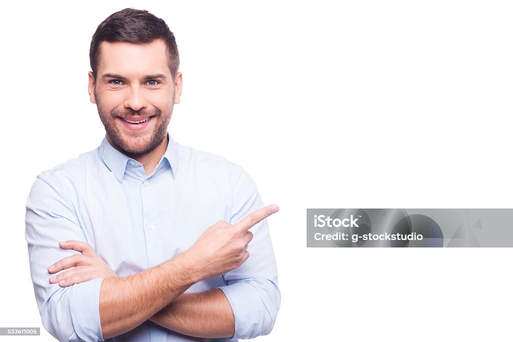 Businessman pointing copy space. Handsome young man in shirt looking at camera and pointing away while standing against white background Pointing Stock Photo