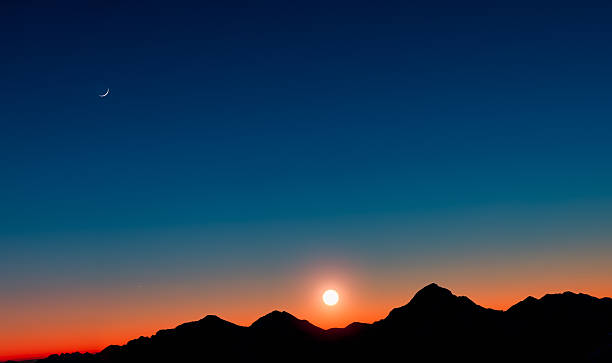 istock Sunset with mountains in silhouette with the moon 533611075