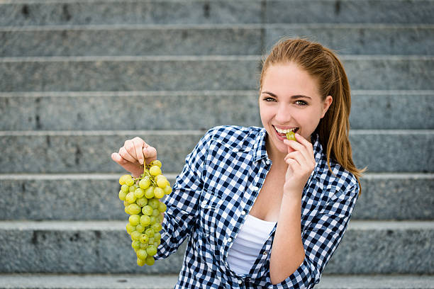 istock Young woman eating  grapes 533612673