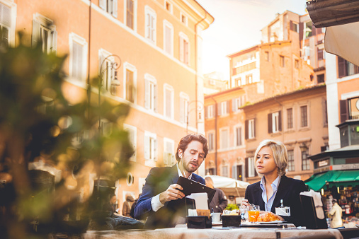 Business couple taking a break, outdoor cafe in Rome downtown.