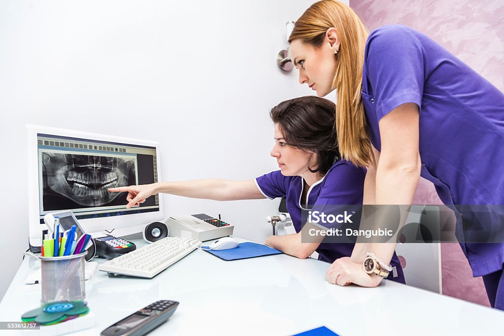 Two Female Dentist Looking At X-ray Image Two Female Dentist Looking At X-ray Image On Computer Screen Dental Assistant Stock Photo