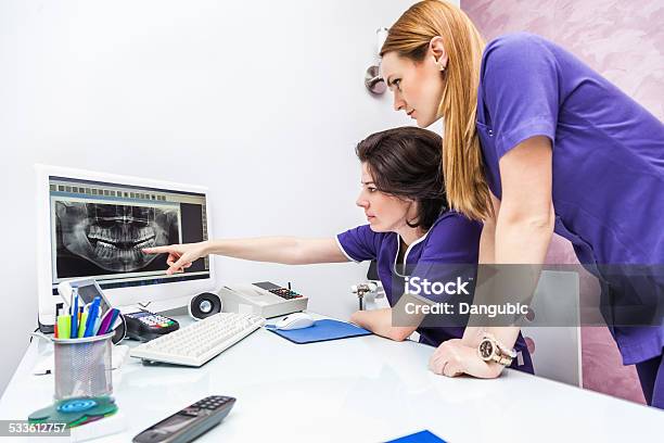 Two Female Dentist Looking At Xray Image Stock Photo - Download Image Now - Dental Assistant, 2015, 30-39 Years