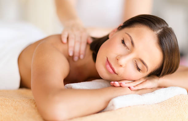 beautiful woman in spa salon getting massage health, beauty, resort and relaxation concept - beautiful woman with closed eyes in spa salon getting massage spa room stock pictures, royalty-free photos & images