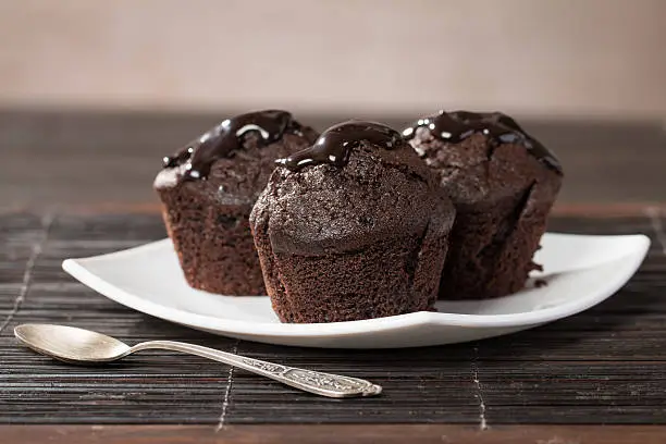 spongecake or muffin with chocolate sauce on wooden beckground