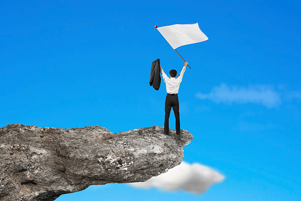 istock Businessman cheering on cliff waving blank flag with sky 533626207