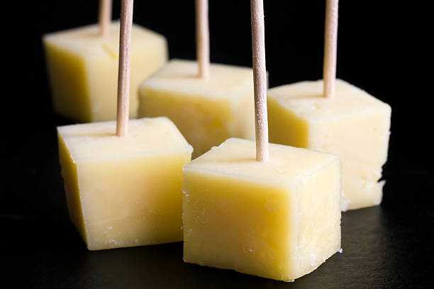 istock Cubes of yellow cheese on toothpicks. Black background. 533632197
