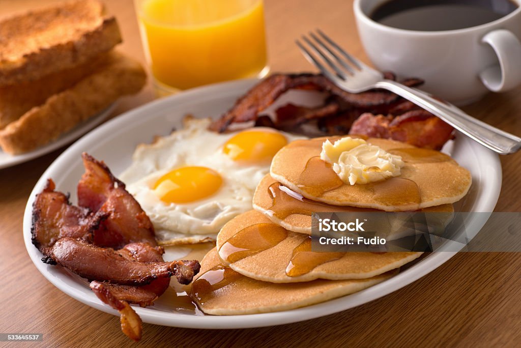 Breakfast with bacon, eggs, pancakes, and toast A delicous home style breakfast with crispy bacon, eggs, pancakes, toast, coffee, and orange juice. Breakfast Stock Photo