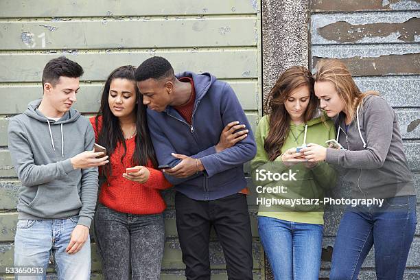 Group Of Teenagers Sharing Text Message On Mobile Phones Stock Photo - Download Image Now