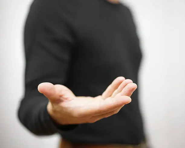 male is standing  and shows outstretched hand with open palm