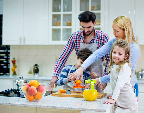 istock Beautiful family preparing orange juice in kitchen 533666819