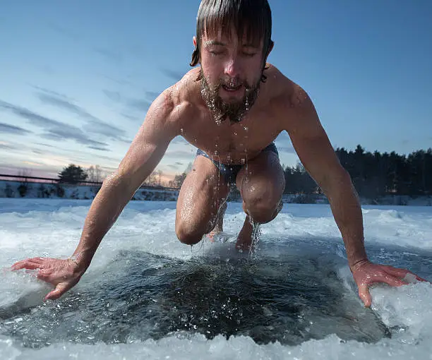 Young man having recreational swim in the ice hole