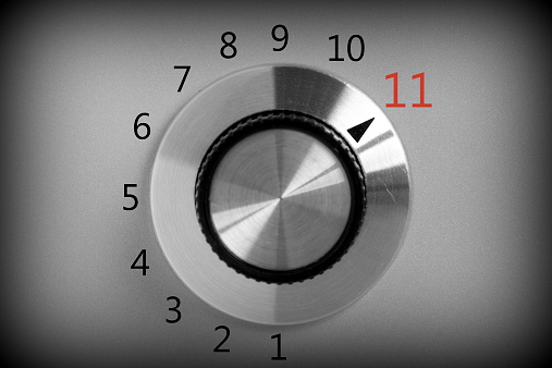Black and white image of a volume or power control switch on a metal background that goes all the way up to the number eleven.