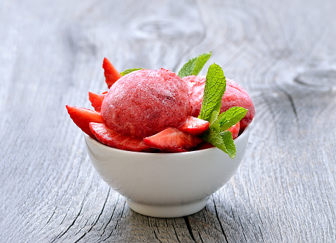 Strawberry sorbet with mint in a bowl on wooden table