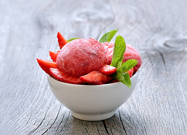 Strawberry sorbet with mint in a bowl on wooden table stock photo
