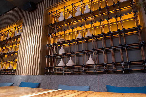 Modern restaurant with wooden table and decorative utensil on shelf at wall